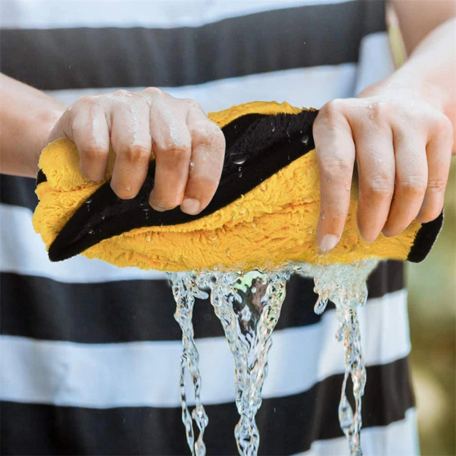 Person wringing out a thick yellow and black microfiber towel during car washing